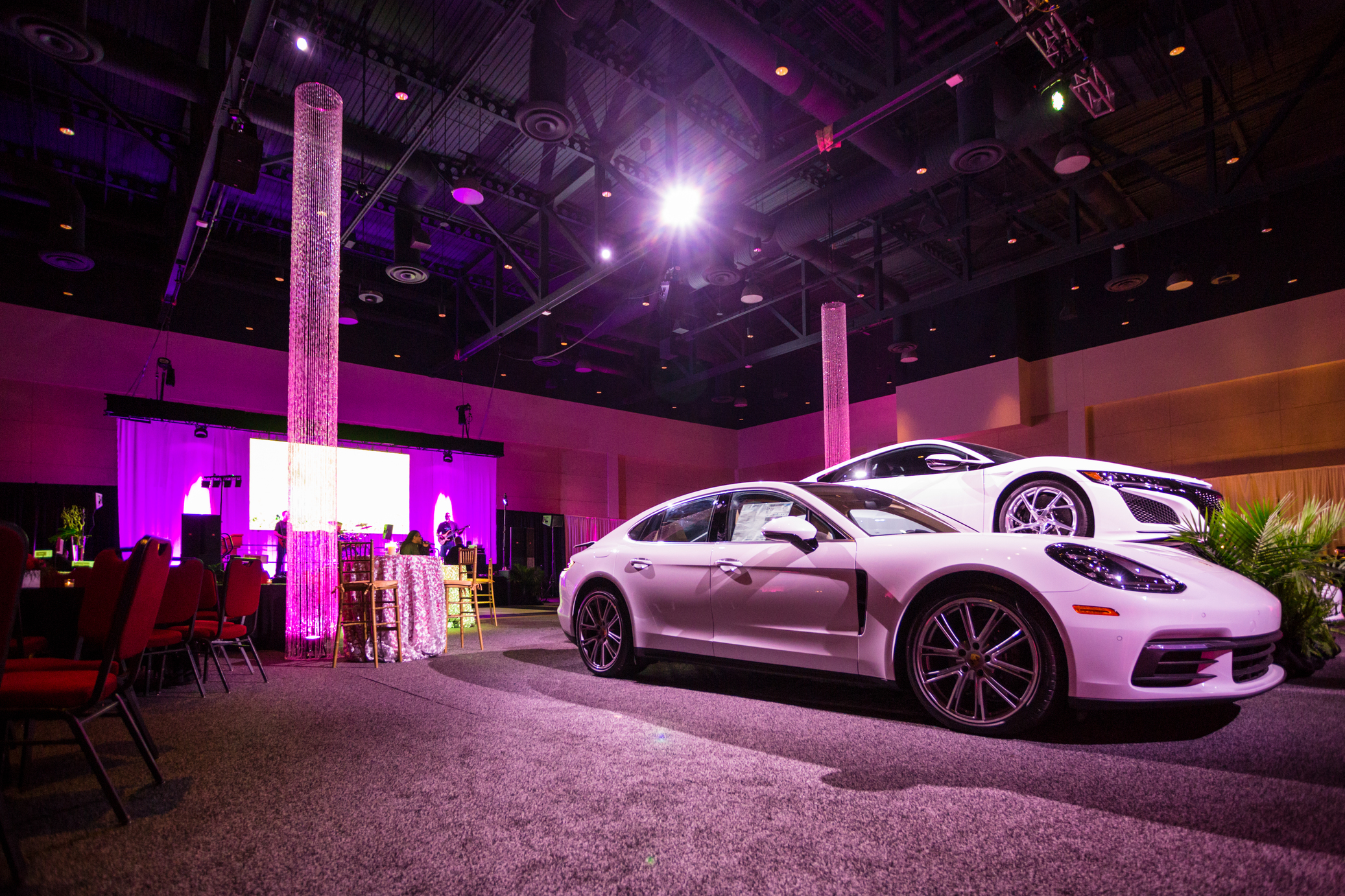 White cars on exhibit with visual equipment creating atmosphere.